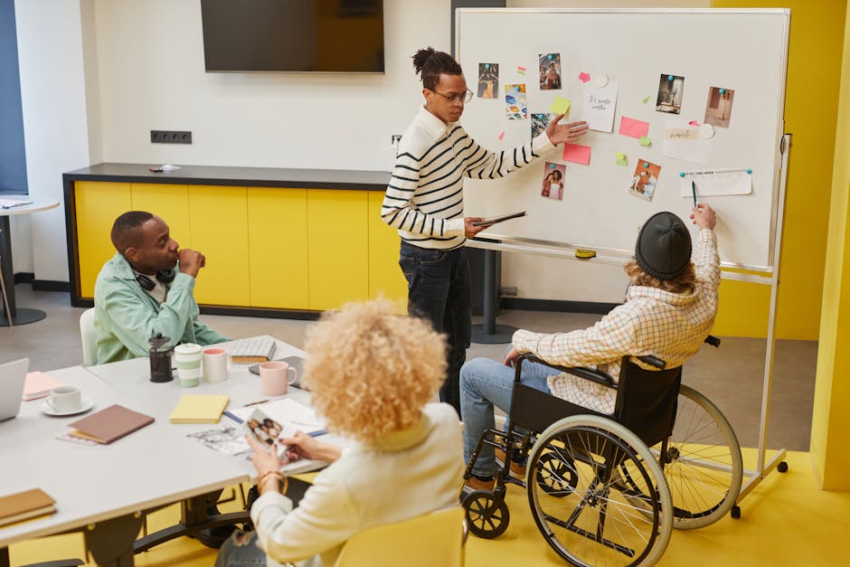 A diverse group of professionals in a creative workspace discussing ideas and planning on a whiteboard.